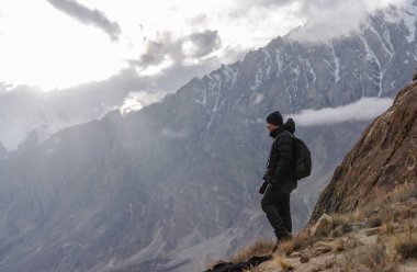 Fotoğrafçı sırt çantası ayakta dağ tepe ve bulutlu gökyüzü ile parlak güneş ışığı ile. Seyahat yaşam tarzı ve başarı başarı kavramı