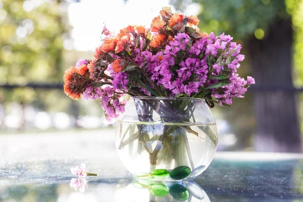 Cam bir masadaki vazoda kurumuş çiçekler.