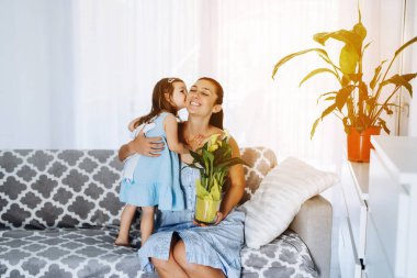 Esmer kadın bebeğini kucaklıyor. Anneler günü hediyesi. Gülümseyen anne küçük kızına sarılıyor. Doğum günü hediyesi.