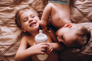 İki küçük çocuk yatağa uzanıp şişede süt içiyorlar. Evde tuhaf çocuklar var.