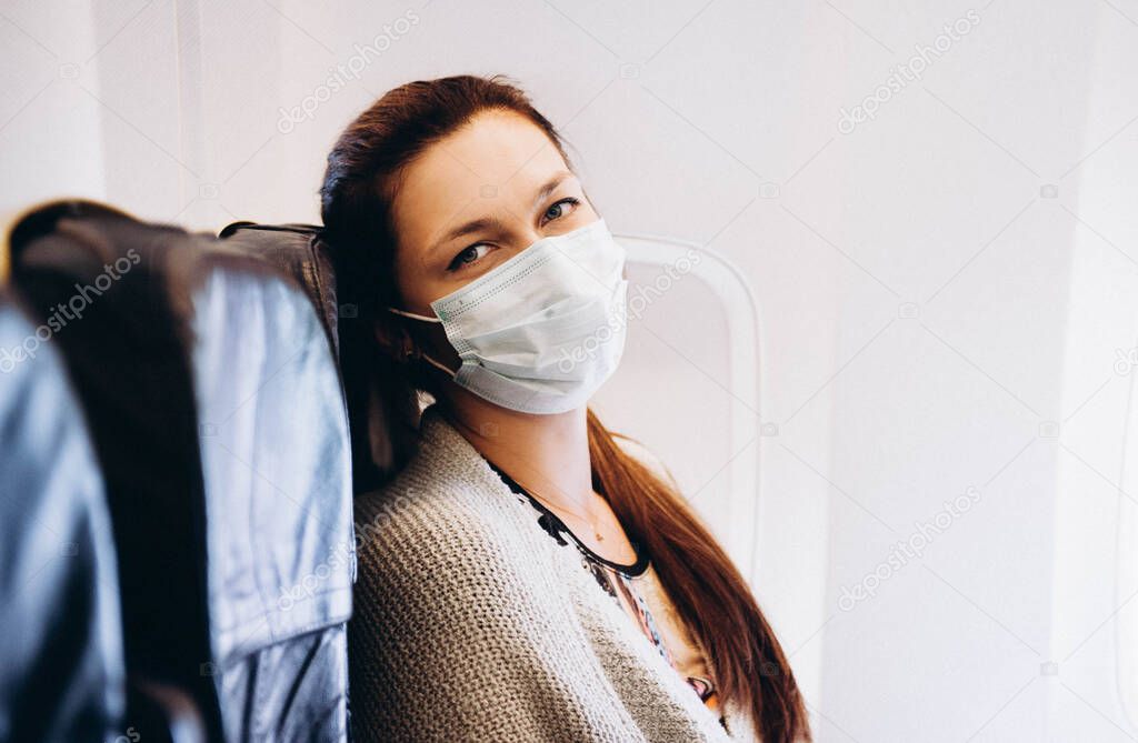 Woman in wearing mask flying in the airplaine. Felling temperature.