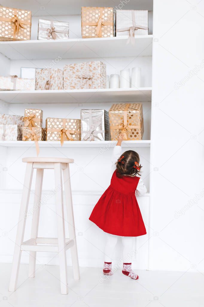 A little girl reaches for her New Years gift to a larger shelf with snackcards