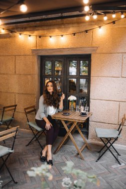 Bir kafede bir bardak kapuçinoyla oturan bir kız.