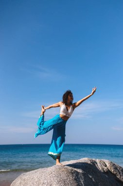 Dandayaman dhanurasana Deniz kenarında bir kayanın üzerinde sabahın erken saatlerinde