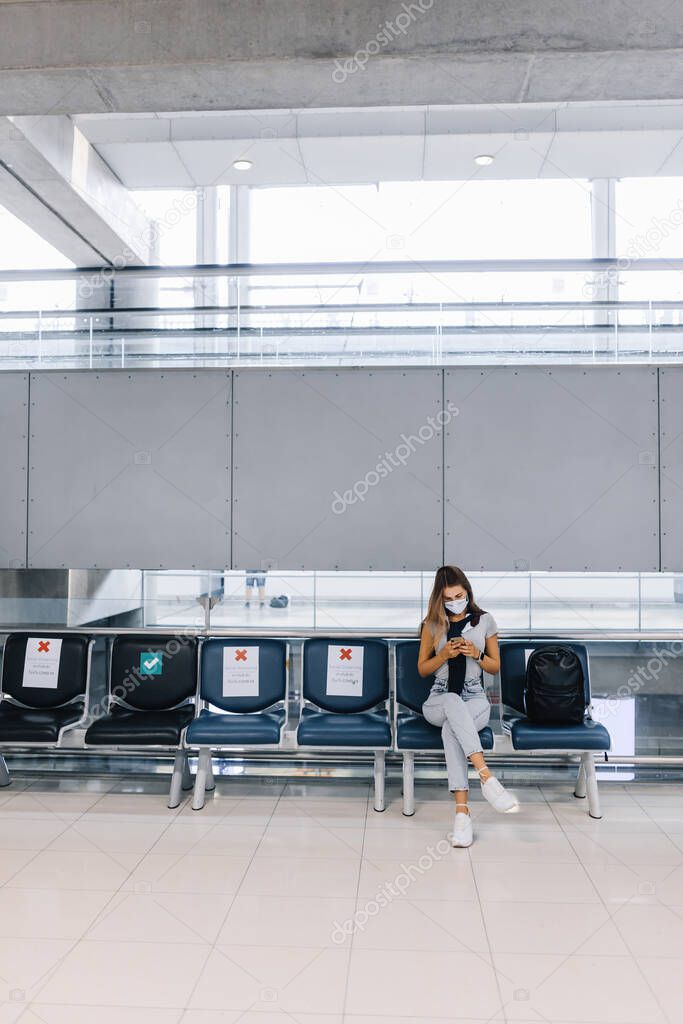 Girl sitting in an empty airport in a mask during a pandemic in Thailand