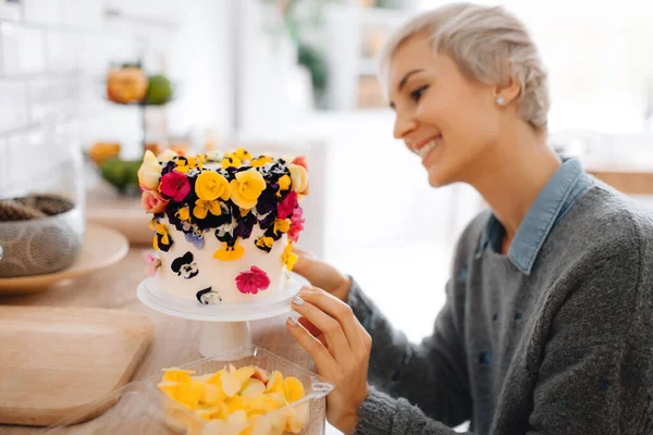 Menina padeiro decora bolo com cores comestíveis em sua cozinha — Fotografia de Stock