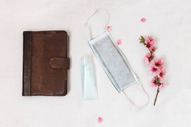 Güvenli karantina kavramı, bir e-kitap, bir dezenfektan, bir maske ve çiçek açan bir sakura dalı.