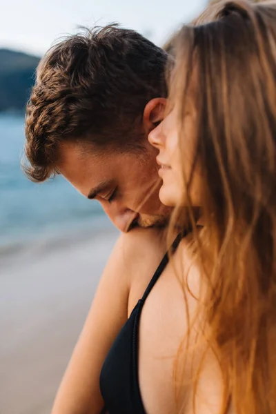 Un hombre besa en la playa a su novia en el hombro en sus vacaciones — Foto de Stock
