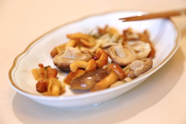 Mantarlar az tuzlu ve sosludur. Bir tabak beyaza ıslaktır ve yemek için çubuklar vardır. 