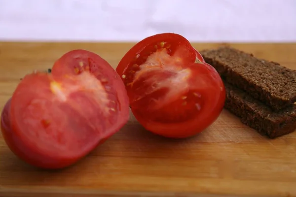 木の板のトマトと黒パンの2枚の側面図 — ストック写真
