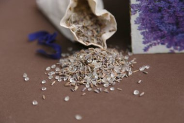 El yapımı kumaş torbada banyo tuzu ve kahverengi masada lavanta tohumu.