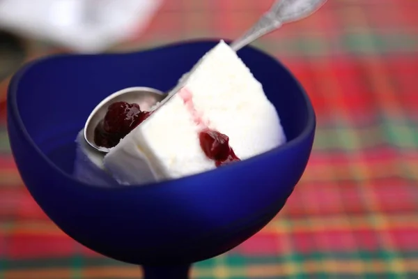 White ice cream with jam in blue glass cup