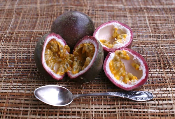 Maracuja fruit with lilac skin and cut into two equal parts, inside flesh and juice, teaspoon on napkin side view