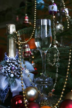 Kapalı şarap şişesi parlak mavi bir banyo ve şarapla süslenmiş arkaplanda Noel ağacı ve Noel ağacı süslemeleri var.