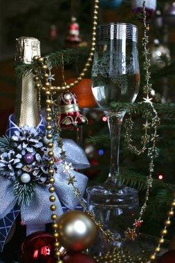 Kapalı şarap şişesi parlak mavi bir banyo ve şarapla süslenmiş arkaplanda Noel ağacı ve Noel ağacı süslemeleri var.