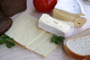Ev yapımı peynir, kat kat peynir, peynir ve bıçak dilimleri peynir ve domatesli yeşillikler.