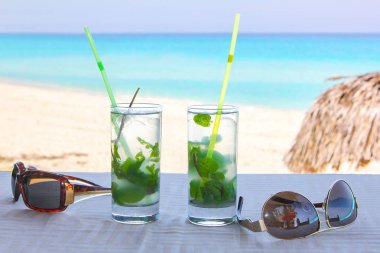 arka plan olarak tablo ve okyanus kıyısında iki mojito