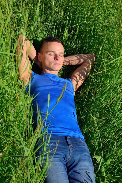 Güneşli bir günde çimlere yatan genç adam