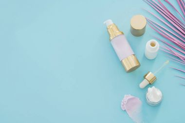 Doğal Cilt Bakımı güzellik ürünleri ile mavi arka plan pembe palmiye yaprağı