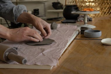 man potter making clay plate in pottery workshop