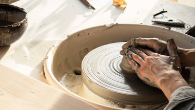 man potter making clay plate in pottery workshop
