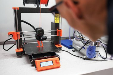 3D yazıcıyı görüntülü olarak kontrol eden adam, laboratuvarda 3D yazıcıda bir şeyler yapma süreci