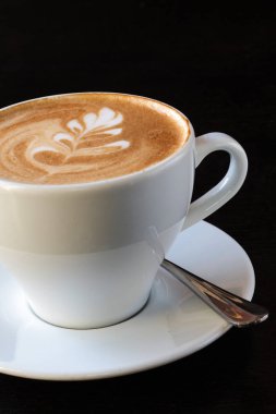 Bir fincan kahve fasulye ve siyah arka plan üzerine tarçın 