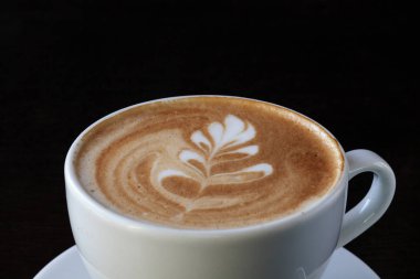 Bir fincan kahve fasulye ve siyah arka plan üzerine tarçın 