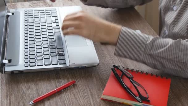 Brazos de hombre escribiendo en el teclado en el escritorio de madera natural — Vídeos de Stock