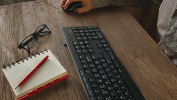 Мужские руки, печатающие на клавиатуре за партой из натуральной древесины — стоковое видео