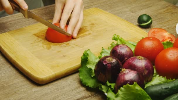 Male hand cutting tomato on cutting board with sharp knife — Stock Video