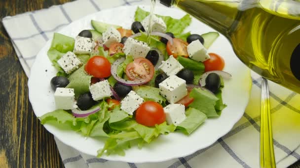 Öl in Schüssel mit griechischem Salat gießen — Stockvideo