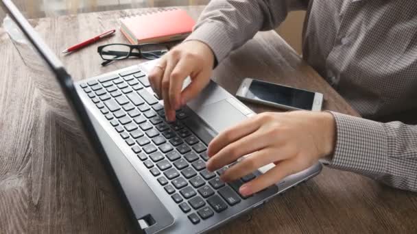 Brazos de hombre escribiendo en el teclado en el escritorio de madera natural — Vídeos de Stock