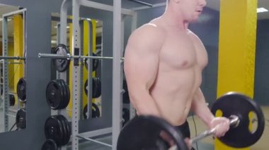 Kaslı adam ile halter, pazı egzersizleri yapıyor spor salonunda egzersiz