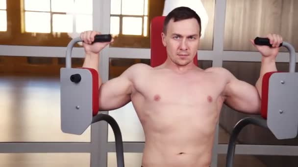 Machine d'exercice de papillon Jeune bodybuilder faisant l'exercice lourd de poids pour la poitrine dans le gymnase — Video