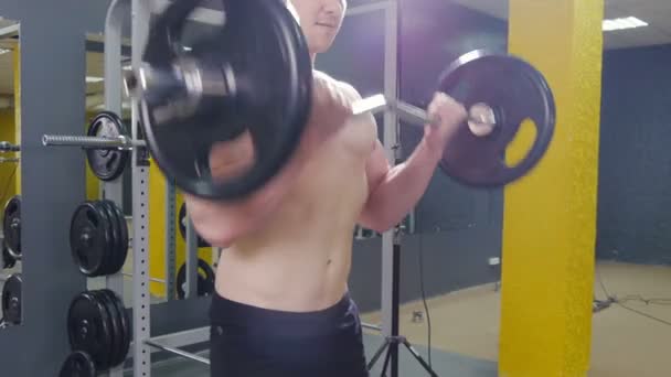 Hombre musculoso haciendo ejercicio en el gimnasio haciendo ejercicios con barra en el bíceps — Vídeos de Stock