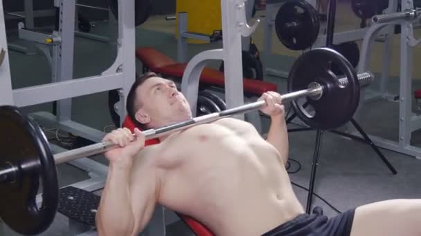 Hombre levantando la barra en el gimnasio . — Vídeos de Stock