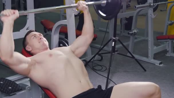 Ung man bänk att trycka vikter på gym — Stockvideo