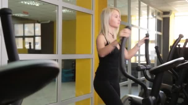 Junge Frau trainiert auf Crosstrainer — Stockvideo