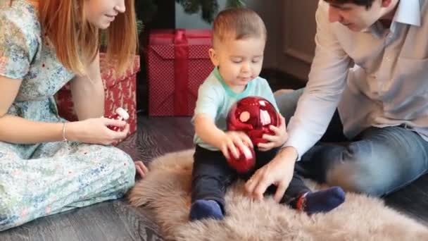 Feliz familia sentada junto al árbol de Navidad — Vídeo de stock