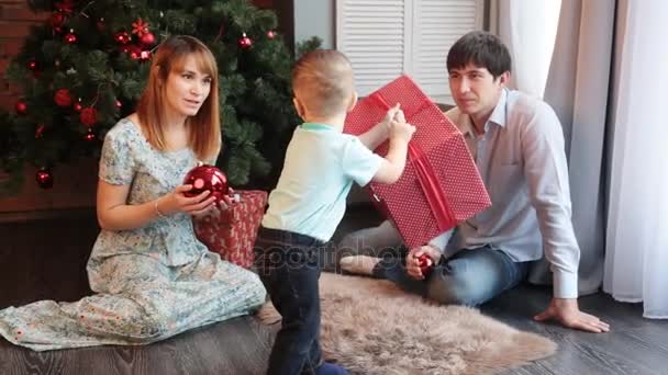 Glückliche Familie sitzt am Weihnachtsbaum — Stockvideo