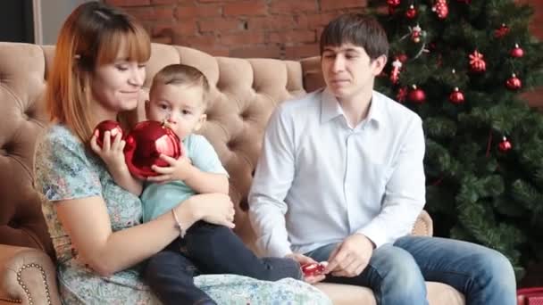 Feliz familia sentada junto al árbol de Navidad — Vídeos de Stock