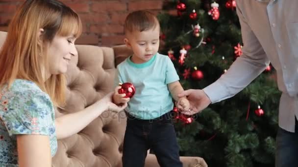 Feliz familia sentada junto al árbol de Navidad — Vídeos de Stock