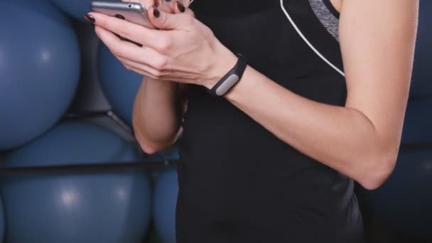 Mujer con reloj de frecuencia cardíaca y smartphone en el gimnasio — Vídeos de Stock