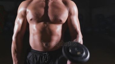 kaslı vücut geliştirmeci biri dumbbells ile yapıyor