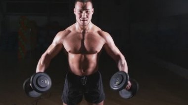 kaslı vücut geliştirmeci biri dumbbells ile yapıyor