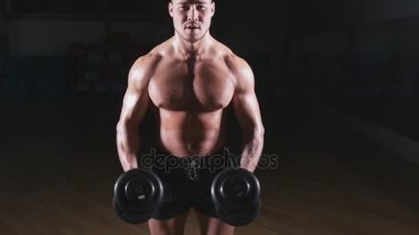 kaslı vücut geliştirmeci biri dumbbells ile yapıyor