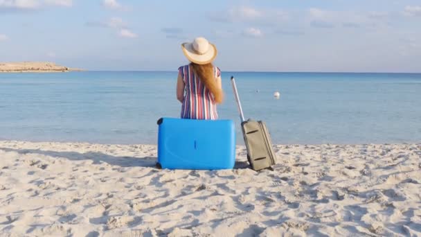 Jonge vrouw reiziger zit op het strand met een koffer — Stockvideo