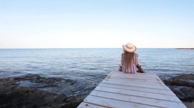 İskele üzerinde oturan genç kadın