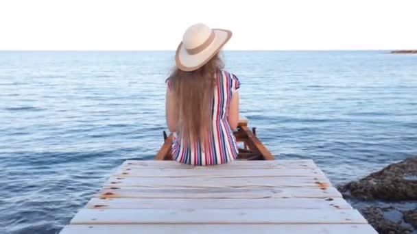Junge Frau sitzt auf Seebrücke — Stockvideo